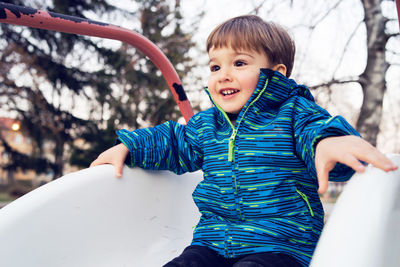 Low angle view of cute boy playing on slide at playground