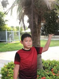 Portrait of boy standing against trees