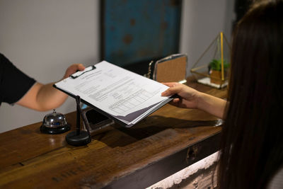 Cropped hand of businessman giving document to coworker in office