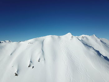 Scenic view of snowcapped mountains against clear blue sky