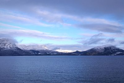 Scenic view of sea by mountains against sky