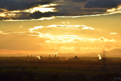 Scenic view of landscape against cloudy sky during sunset