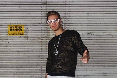 Portrait of young man standing against wall