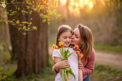 Mother holding flowers kissing daughter