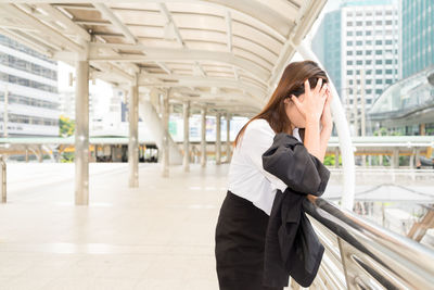 Side view of sad woman standing on elevated walkway