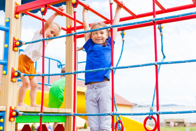 Low angle view of siblings on slide at playground