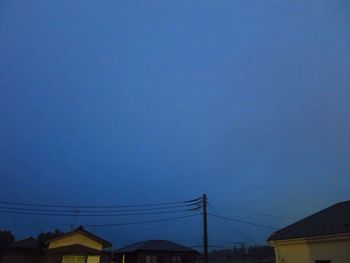 Low angle view of electricity pylon against blue sky