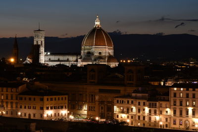 Illuminated buildings in city against sky