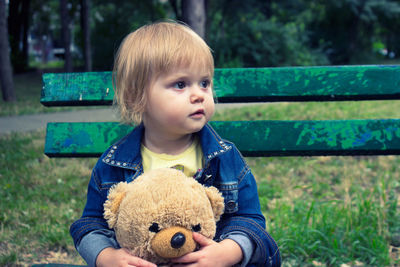 Portrait of cute boy with toy sitting outdoors