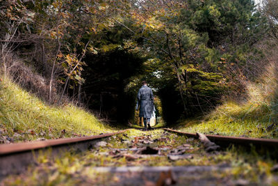 Rear view of person walking on railroad track