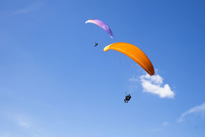 Low angle view of person paragliding against clear blue sky