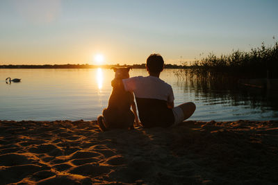 Lake jamno, poland - boy and his dog on lake at sunset