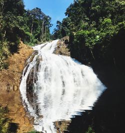 Scenic view of waterfall in forest against sky