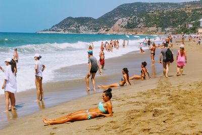 People enjoying at beach against sky