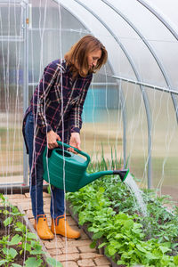 Young woman holding food while standing by plant