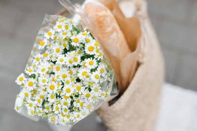 Bouquet of chamomile in a straw bag on a chair outdoors.