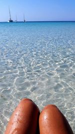 Midsection of woman at beach against sky