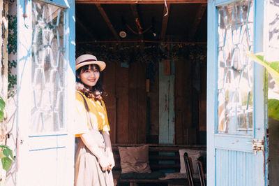 Portrait of smiling young woman standing against entrance