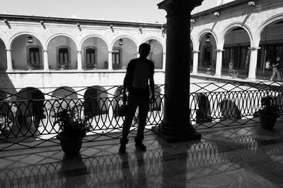 Rear view of silhouette man standing by railing in city