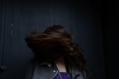 Woman tossing hair while standing against wall