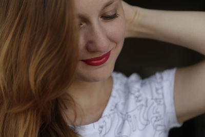 Close-up of beautiful young woman with hand in hair looking down