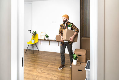 Mature man unpacking things from boxes while moving in new apartment.