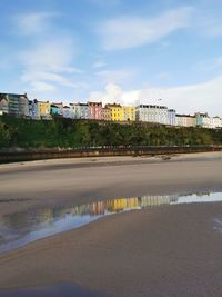 Reflection of buildings on river against sky in city