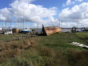 Sailboats moored on field against sky