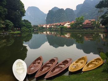 Reflection of houses and mountains in a lake with kayaks on one side and gear drying on the other