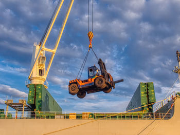 The ship's crane is moving forklift and special tool to operate cargo on board.