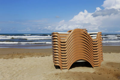 Lounge chairs on sand at beach against sky