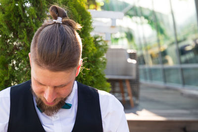 Waiter with man bun in front of restaurant