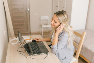 Young woman using mobile phone in laptop