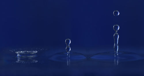 Close-up of drop falling on water against black background