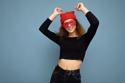 Portrait of young woman standing against blue background