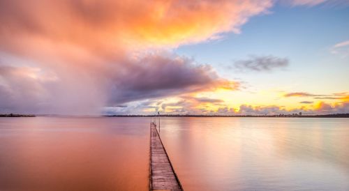 Scenic view of sea against dramatic sky during sunset