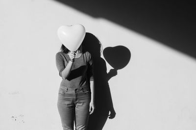 Midsection of woman holding balloon standing against wall