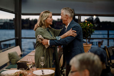 Smiling senior couple greeting each other in restaurant