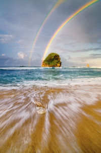 Scenic view of rainbow over sea against sky