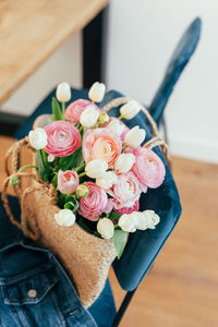 Beautiful bouquet of white tulips and pastel pink and peach ranunculus in a jute bag.