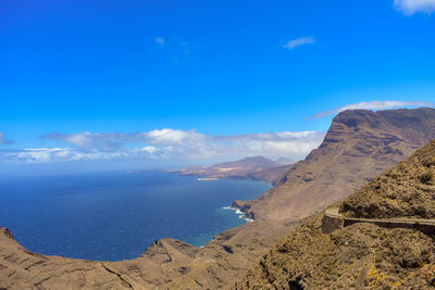 Scenic view of sea and mountains against blue sky