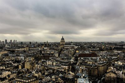 High angle view of city buildings against cloudy sky