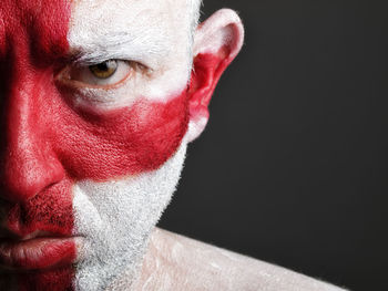 Close-up portrait of serious man with english flag body paint against black background