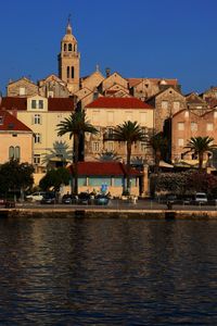 Buildings by canal against blue sky in city