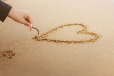 Cropped hand making heart shaped at beach