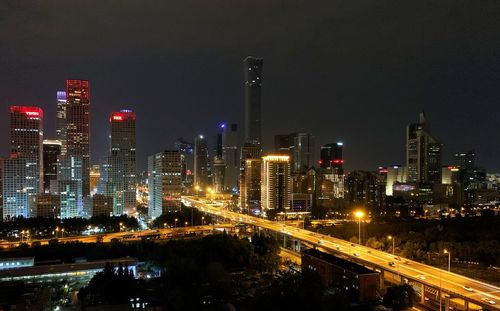 Illuminated modern buildings in city against sky at night