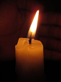 Close-up of illuminated candle in darkroom