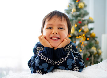 Portrait of cute baby boy lying on bed at home