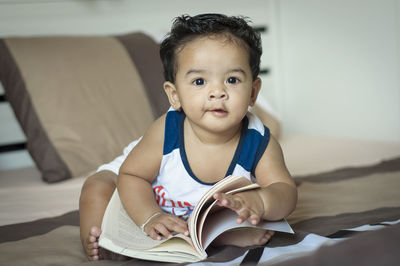 Portrait of boy sitting on book at home