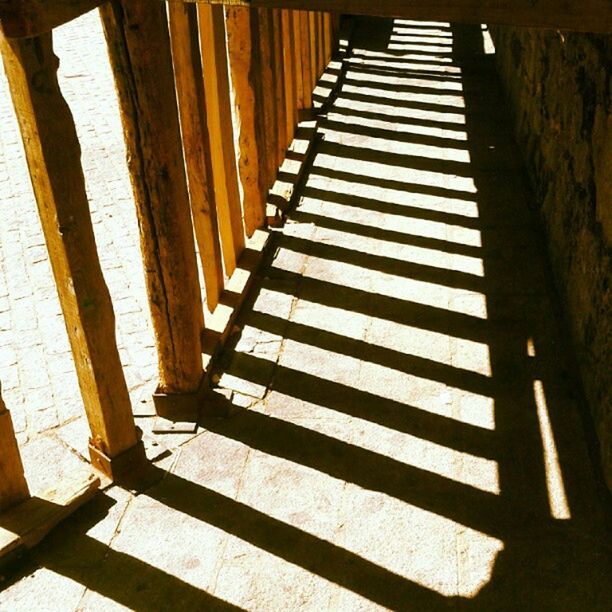 steps, steps and staircases, staircase, railing, indoors, the way forward, shadow, sunlight, in a row, built structure, pattern, diminishing perspective, wood - material, architecture, high angle view, stairs, empty, no people, day, walkway